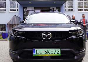 Samochód elektryczny przed wejściem do szkoły