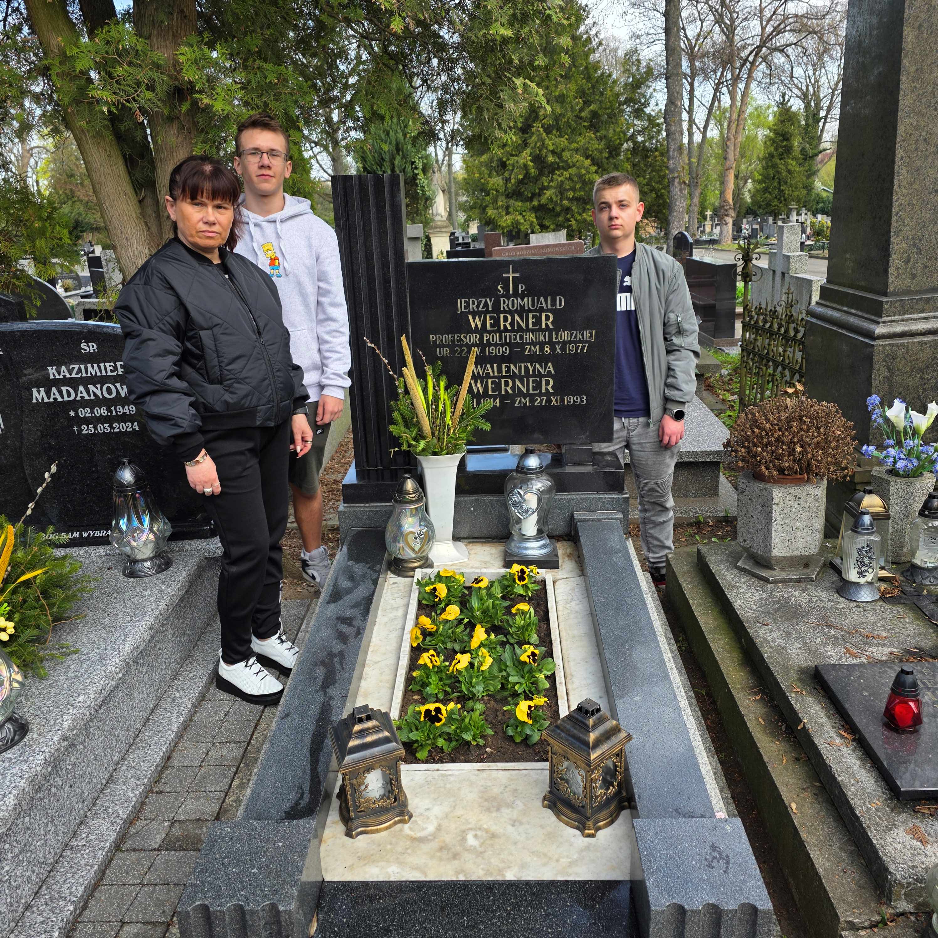 Przy grobie prof. Jerzego Wernera stoją trzy osoby. Nauczycielka i uczniowie.