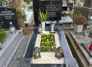 Widok nagrobka profesora Jerzego Wernera. Na grobie zapalone są znicze i rosną żółte bratki.