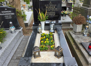 Widok nagrobka profesora Jerzego Wernera. Na grobie zapalone są znicze i rosną żółte bratki.
